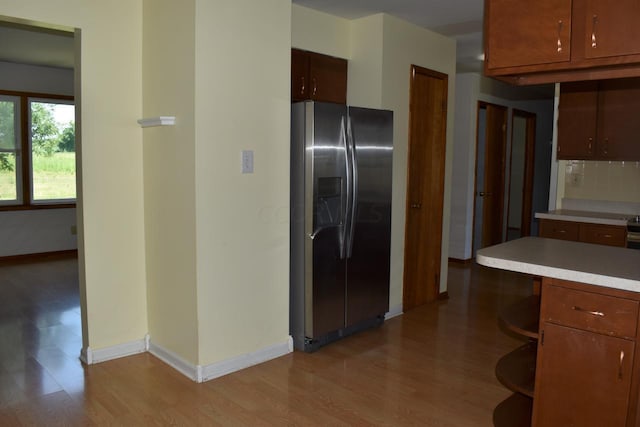 kitchen featuring stainless steel fridge, light wood-type flooring, and backsplash