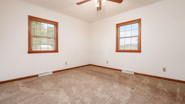 spare room with carpet floors, a wealth of natural light, and ceiling fan