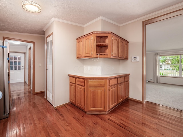 kitchen with light hardwood / wood-style floors, a textured ceiling, and ornamental molding