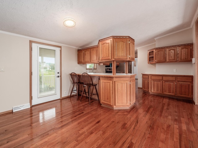 kitchen featuring kitchen peninsula, dark hardwood / wood-style flooring, a textured ceiling, vaulted ceiling, and crown molding