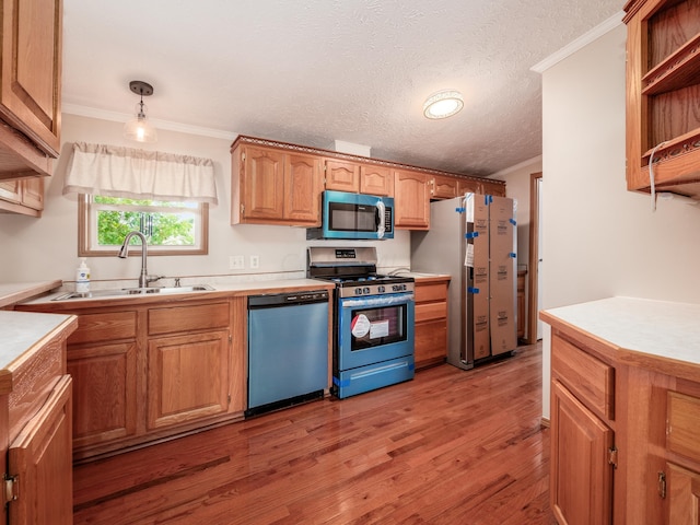 kitchen featuring sink, hardwood / wood-style floors, decorative light fixtures, appliances with stainless steel finishes, and ornamental molding