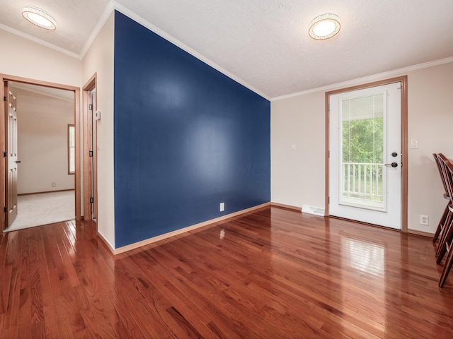 foyer with wood-type flooring, a textured ceiling, and crown molding