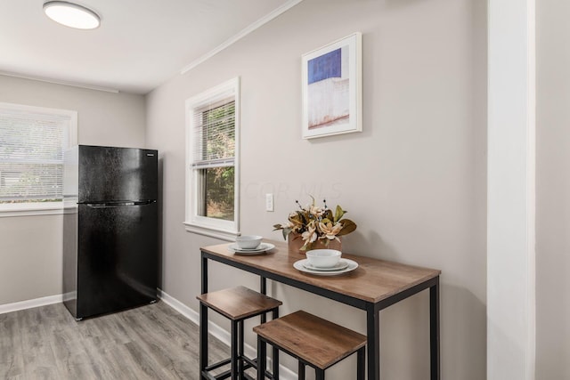 kitchen featuring wood counters, light hardwood / wood-style floors, black fridge, and ornamental molding