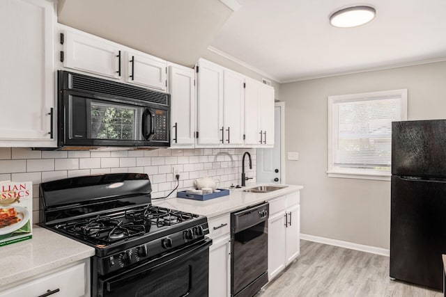 kitchen featuring white cabinetry, ornamental molding, black appliances, and light wood-type flooring