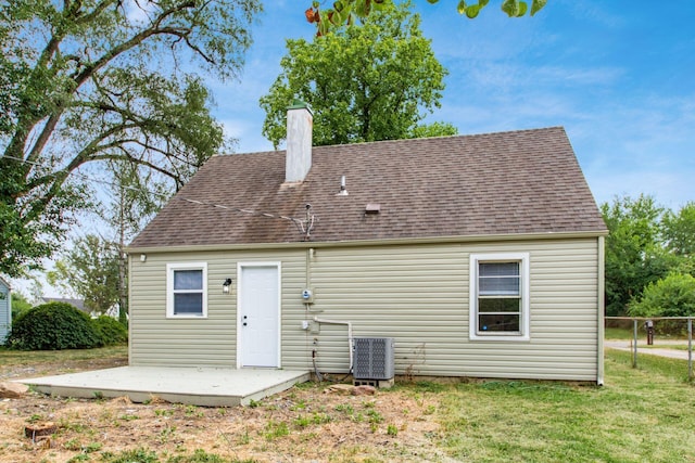 back of property with central air condition unit and a yard