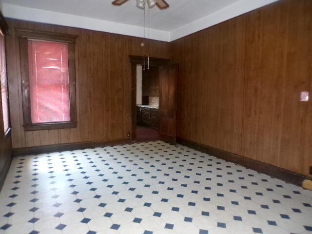 empty room featuring wood walls and ceiling fan