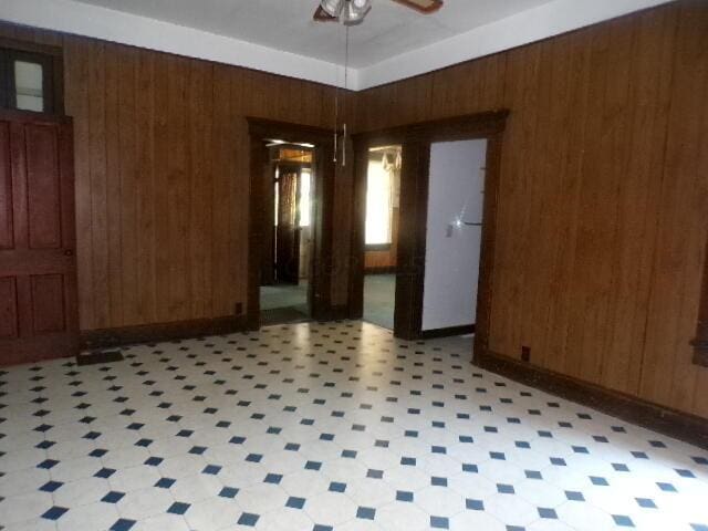 unfurnished room featuring ceiling fan and wood walls