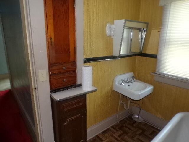 bathroom with wood walls, parquet floors, and sink