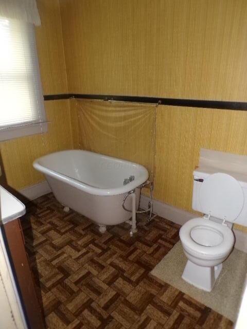 bathroom with a bathing tub, vanity, toilet, and parquet floors