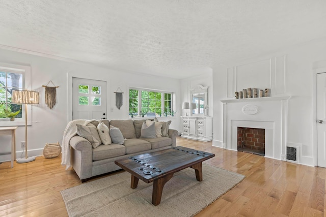 living room featuring plenty of natural light, light hardwood / wood-style floors, and a textured ceiling