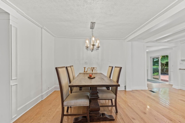 dining area with light hardwood / wood-style flooring, a textured ceiling, and an inviting chandelier