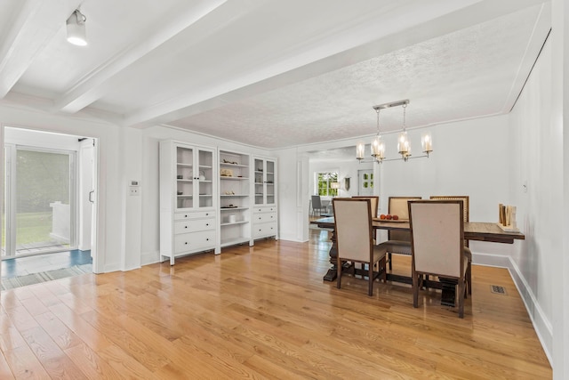 dining area featuring beam ceiling, light hardwood / wood-style floors, a textured ceiling, and a notable chandelier