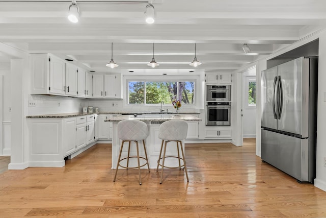 kitchen featuring a center island, white cabinets, beamed ceiling, plenty of natural light, and stainless steel appliances