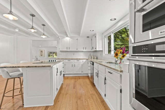 kitchen featuring white cabinets, sink, light wood-type flooring, a kitchen island, and light stone counters