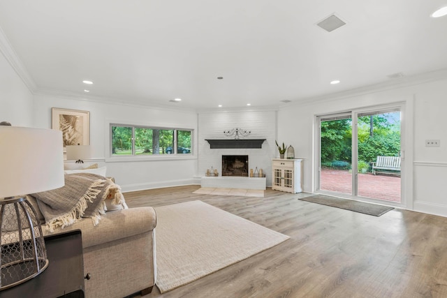 living room with a large fireplace, crown molding, plenty of natural light, and light wood-type flooring