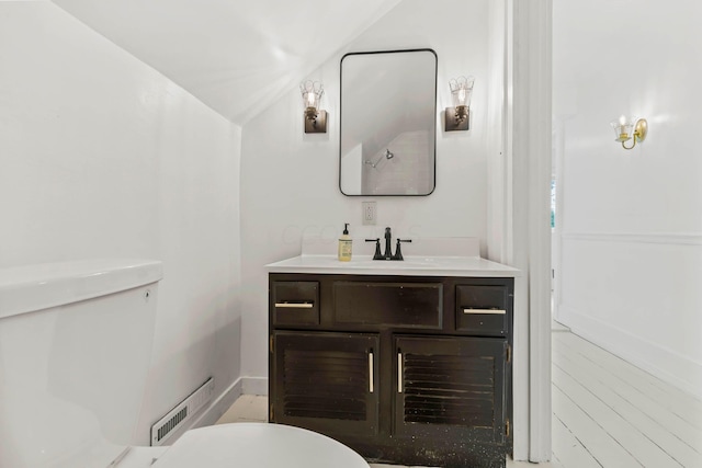 bathroom with vanity, toilet, and lofted ceiling