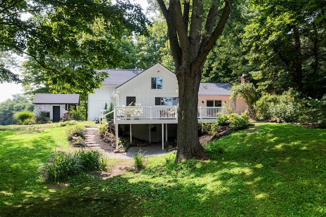 back of house with a lawn, an outbuilding, and a wooden deck