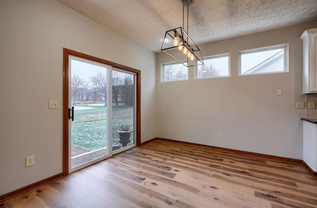 7265 Bromfield Dr, Canal Winchester, OH 43110 - unfurnished dining area with a textured ceiling, wood finished floors, plenty of natural light, and a chandelier