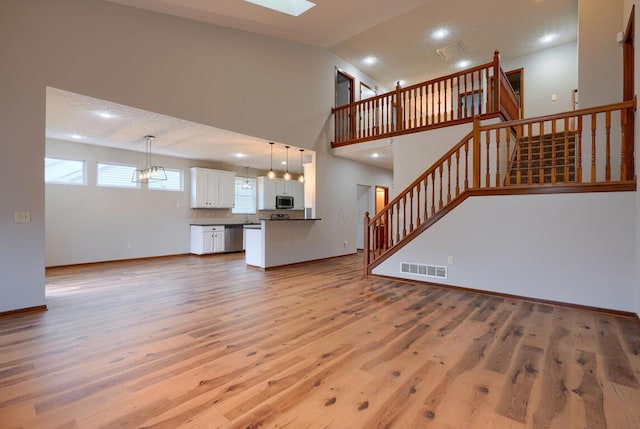 7265 Bromfield Dr, Canal Winchester, OH 43110 - unfurnished living room with light wood-style floors, stairway, recessed lighting, a skylight, and high vaulted ceiling