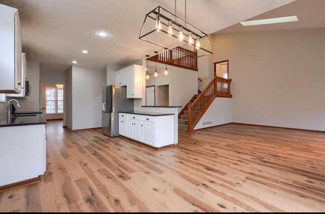 7265 Bromfield Dr, Canal Winchester, OH 43110 - kitchen featuring appliances with stainless steel finishes, dark countertops, a textured ceiling, light wood finished floors, and white cabinetry