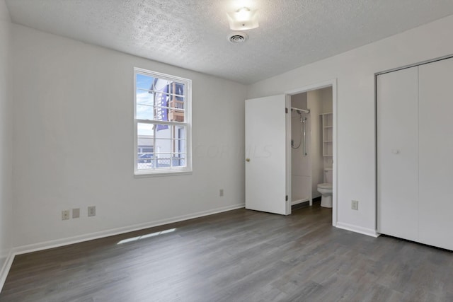 unfurnished bedroom featuring wood-type flooring, connected bathroom, and a textured ceiling