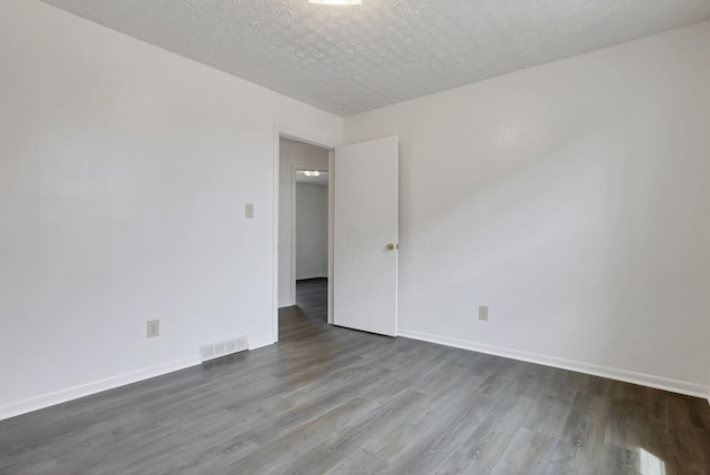 spare room with a textured ceiling and dark hardwood / wood-style flooring