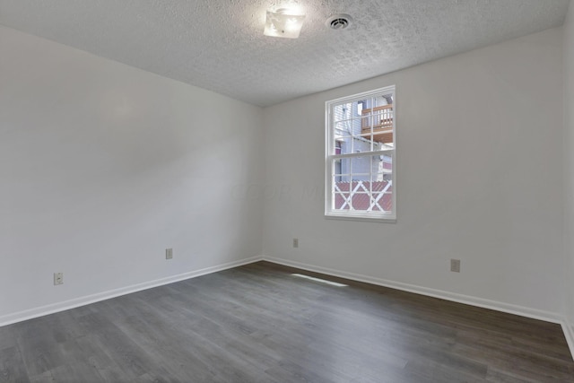 empty room featuring a textured ceiling and dark wood-type flooring