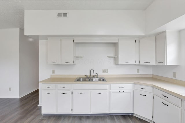 kitchen featuring dark hardwood / wood-style flooring, white cabinetry, sink, and a textured ceiling