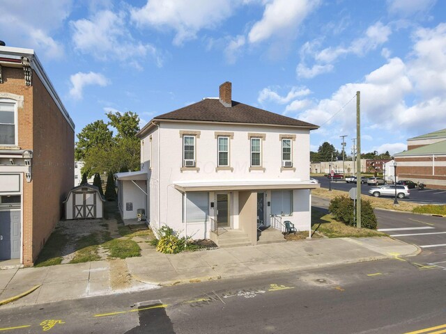 45 S 5th St, Newark, OH 43055 - view of front of property with a storage shed, a chimney, stucco siding, and roof with shingles