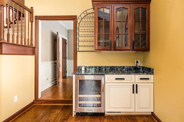 bar featuring ornamental molding, dark hardwood / wood-style flooring, wine cooler, and dark stone counters