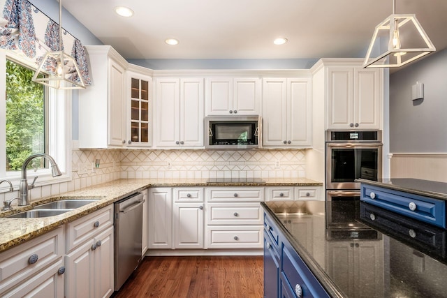 kitchen featuring pendant lighting, dark stone counters, sink, white cabinetry, and stainless steel appliances