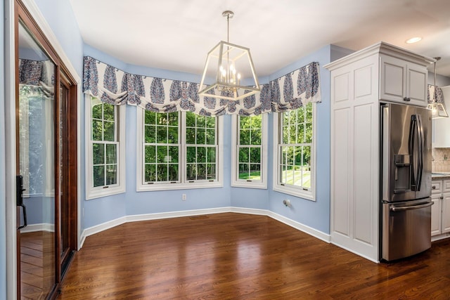 unfurnished dining area featuring dark hardwood / wood-style flooring, a healthy amount of sunlight, and a notable chandelier