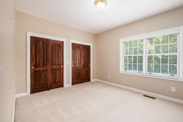 unfurnished bedroom featuring light carpet and a closet