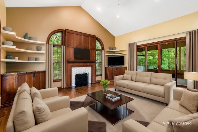 living room with a wealth of natural light, high vaulted ceiling, and light hardwood / wood-style floors