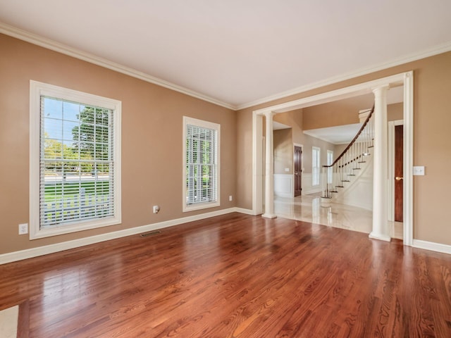 unfurnished room featuring wood-type flooring, ornate columns, and crown molding