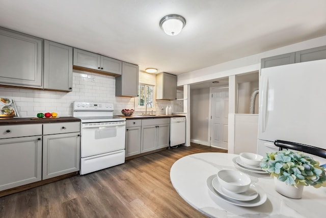 kitchen with white appliances, backsplash, dark wood-type flooring, sink, and gray cabinets