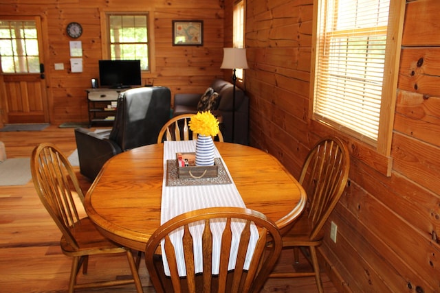 dining room featuring wood-type flooring and wooden walls