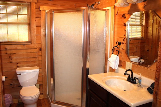 bathroom with a shower with door, vanity, wooden walls, and toilet