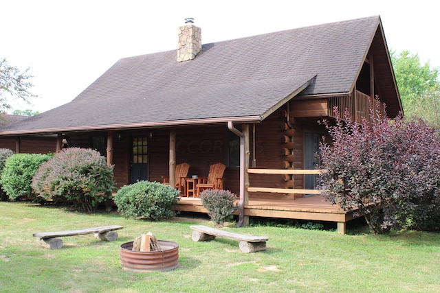 back of property with a yard and a fire pit