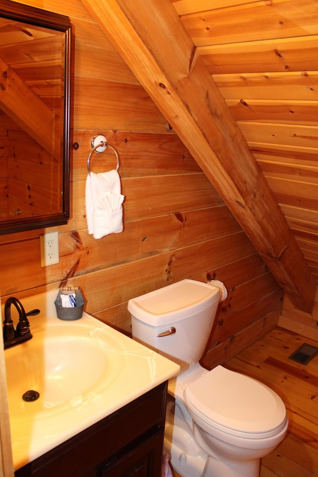 bathroom with toilet, vanity, and wooden walls