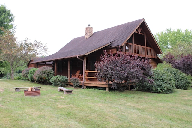 back of house featuring a wooden deck, a yard, and a fire pit