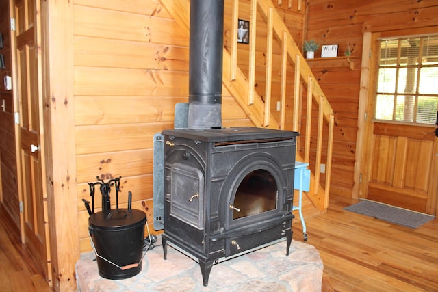 room details featuring a wood stove, hardwood / wood-style floors, and wood walls