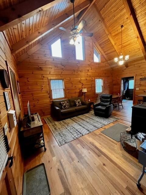 interior space with ceiling fan with notable chandelier, wooden walls, wood-type flooring, wooden ceiling, and beam ceiling