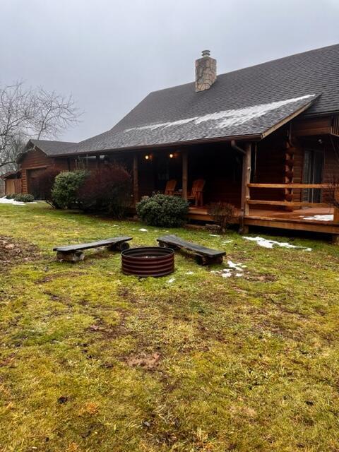 back of property featuring a wooden deck and a yard