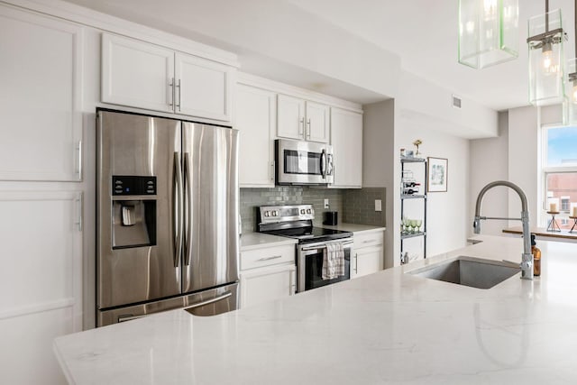 kitchen featuring white cabinetry, light stone countertops, sink, tasteful backsplash, and appliances with stainless steel finishes