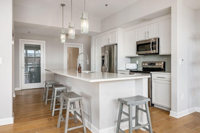 kitchen featuring white cabinetry, stainless steel appliances, and a kitchen island with sink