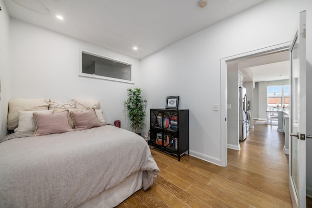 bedroom featuring stainless steel refrigerator with ice dispenser and light wood-type flooring