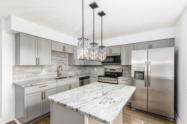 kitchen featuring sink, a center island, hanging light fixtures, light hardwood / wood-style flooring, and appliances with stainless steel finishes