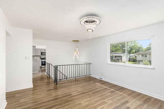 empty room featuring a chandelier and wood-type flooring