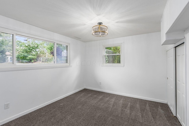 unfurnished bedroom with a closet, dark carpet, and an inviting chandelier